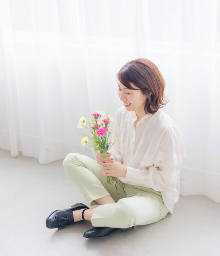 花を見てほほ笑む代表の写真